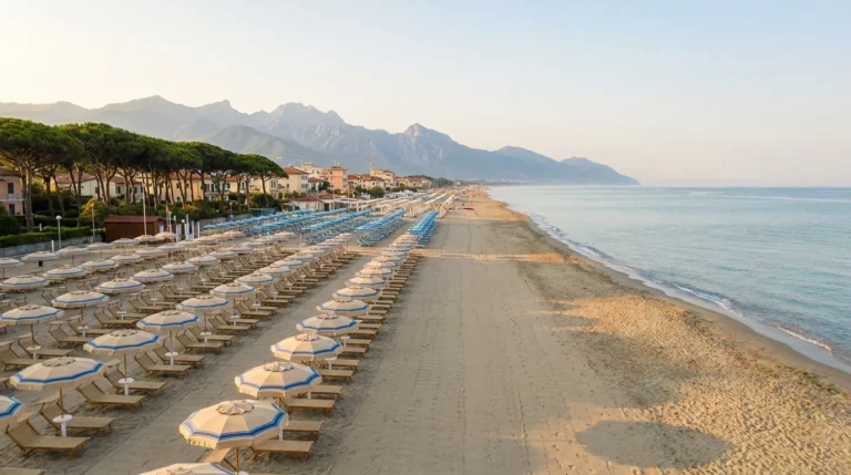 File di ombrelloni tra mare e Apuane